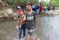Seorang ibu dan bayinya, terpaksa menyeberangi Kali Dagemage di Desa Kolisia Kecamatan Magepanda, Jumat (18/1)