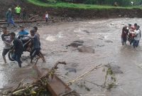 Sekelompok anak muda mengevakuasi motor melewati Kali Magerepu akibat jembatan darurat di lokasi itu hanyut terbawa banjir bandang, Selasa (29/1)