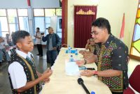 Anggota Komisi I DPR RI andreas Hugo Pareira sedang menyerahkan beasiswa Program Indonesia Pintar kepada salah satu siswa