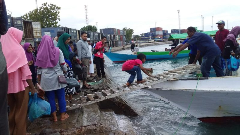 Seorang anak kecil yang hendak mudik ke Desa Kojadoi, Senin (3/6), terpaksa berjongkok di atas jembatan darurat untuk menuju ke kapal motor penumpang