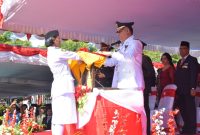 Bupati Sikka Fransiskus Roberto Diogo menyerahkan bendera merah putih kepada Pasukan Pengibar Bendera (Paskibra) untuk dikibarkan di Lapangan Umum Kota Baru Maumere, Sabtu (17/8)
