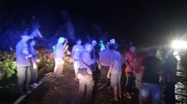 Aparat kepolisian menyingkirkan pohon tumbang yang menutup badan jalan, Minggu (29/12)