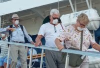 Wisman turun dari Coral Adventurer dengan mengenakan masker, Senin (17/2)