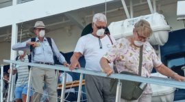 Wisman turun dari Coral Adventurer dengan mengenakan masker, Senin (17/2)