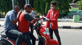 Ketua GMNI Sikka sedang membagikan masker gratis kepada pelintas jalan di Jalan Ahmas Yani Maumere, Senin (23/3)