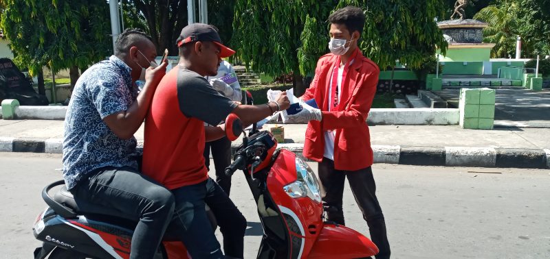 Ketua GMNI Sikka sedang membagikan masker gratis kepada pelintas jalan di Jalan Ahmas Yani Maumere, Senin (23/3)
