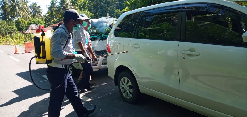 Petugas Dishub Sikka sedang menyemprot cairan disinfektan ke mobil yang melintasi perbatasan Kabupaten Sikka dan Kabupaten Ende, Senin (30/3)