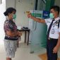Petugas keamanan pada Kantoe BPJS Kesehatan Maumere sedang mengukur suhu tubuh salah satu peserta JKN-KIS
