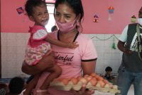 Seorang ibu menerima 1 papan telur ayam dari wartawan, Selasa (22/12)