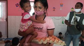 Seorang ibu menerima 1 papan telur ayam dari wartawan, Selasa (22/12)