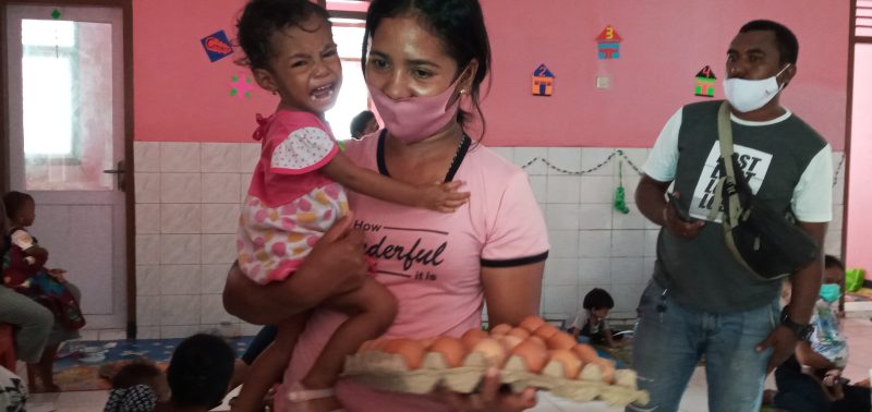 Seorang ibu menerima 1 papan telur ayam dari wartawan, Selasa (22/12)