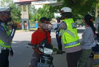 Seorang polisi wanita mengenakan masker kepada pelanggar prokes, Selasa (23/2)
