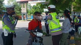 Seorang polisi wanita mengenakan masker kepada pelanggar prokes, Selasa (23/2)
