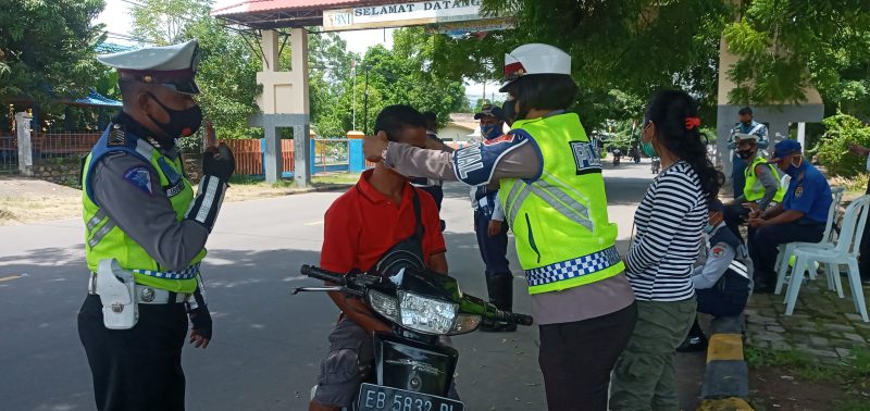 Seorang polisi wanita mengenakan masker kepada pelanggar prokes, Selasa (23/2)
