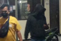 Seorang penyidik mengawal pemuda yang menantang keganasan Covid, Jumat (23/7) malam