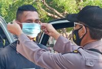 Seorang polisi memakaikan masker kepada sopir pikup, Selasa (27/7)

