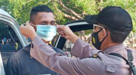 Seorang polisi memakaikan masker kepada sopir pikup, Selasa (27/7)
