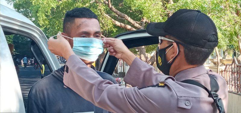 Seorang polisi memakaikan masker kepada sopir pikup, Selasa (27/7)
