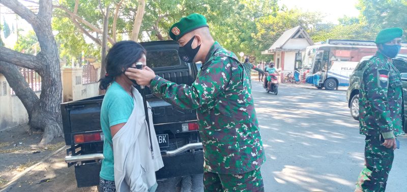 Dandim Sikka memakaikan masker kepada Anastasia, salah seorang pengunjung Pasar Alok, Selasa (24/8)
