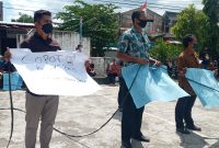 Seorang peserta aksi memegang poster yang mendesak pencopotan Kadis PKO Sikka, Jumat (3/9)
