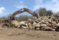 Exavator sedang menumpukkan batu-batu galian di lokasi Pemakaman Covid (foto: istimewa)