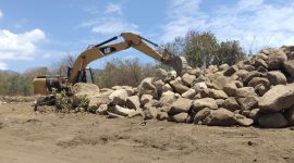 Exavator sedang menumpukkan batu-batu galian di lokasi Pemakaman Covid (foto: istimewa)