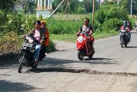 Kendaraan roda dua terpaksa melintas pada sisi kanan untuk menghindar jalan berlubang besar di Maumere, Selasa (1/3)