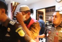 Mantan Kepala BPBD Sikka Mohammad Daeng Bakir berjakan ke mobil tahanan sambil menutup wajah, Rabu (8/2) 