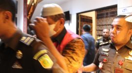 Mantan Kepala BPBD Sikka Mohammad Daeng Bakir berjakan ke mobil tahanan sambil menutup wajah, Rabu (8/2) 