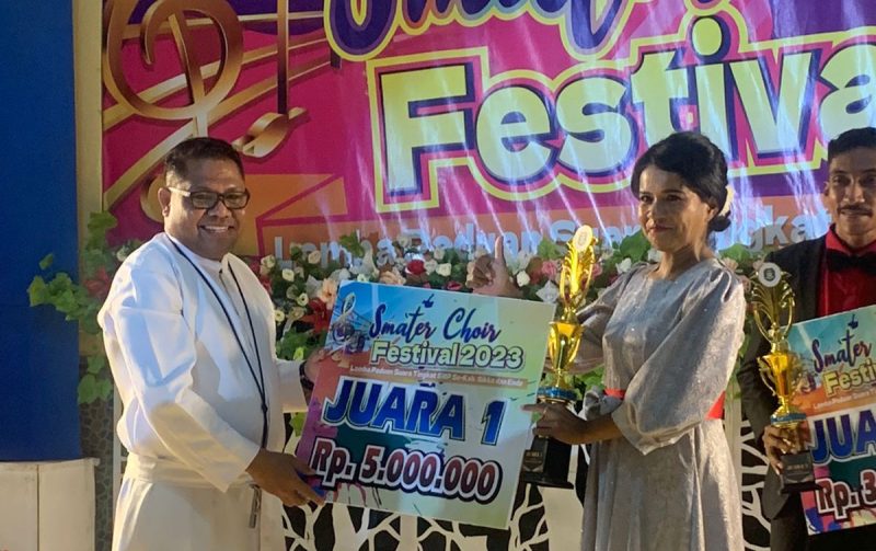 Pimpinan Paduan Suara SMPK Frater Maumere Maria Redempta Priska menerima hadiah kejuaraan Smater Choir Festival 2023