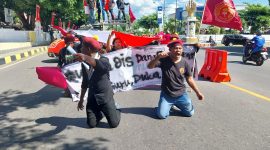 Massa aksi PMKRI Maumere berlutut di depan Mapolres Sikka saat diputarkan lagu Hymne Guru, Senin (24/7)  