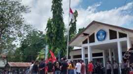 Demonstran GMNI Sikka menurunkan bendera hingga setengah tiang di Kantor Dinas PKO Sikka, Senin (16/10) 