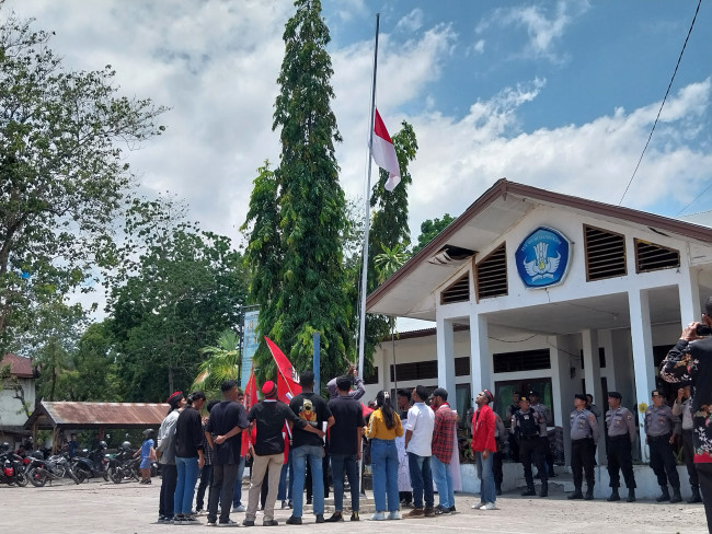 Demonstran GMNI Sikka menurunkan bendera hingga setengah tiang di Kantor Dinas PKO Sikka, Senin (16/10) 