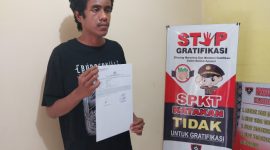 Korban penganiayaaan memperlihatkan dokumen laporan kepolisian, Selasa (25/6)