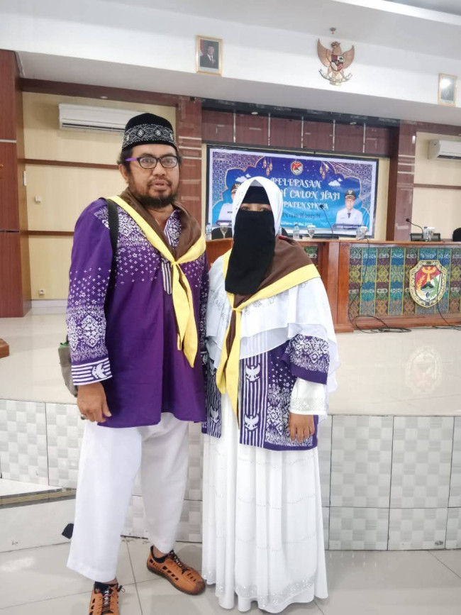 Rudi Susanto pose bersama istri saat acara pelepasan jemaah calon haji pada Mei 2025 