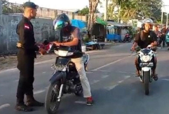 Personil Brimob Maumere membagikan bendera Merah Putih menjelang HUT ke-80 Kemerdekaan RI, Minggu (3/8)