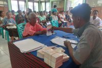 Seorang penerima PKH menerima buku rekening BRI dari pendamping PKH, Jumat (24/10)