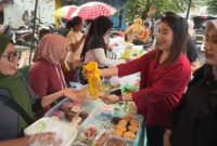 Seorang staf BRI Maumere memberikan minyak goreng kepada saat kepada pedagang takjil di Kampung Beru yang tertarik pada Qris, Kamis (19/2)