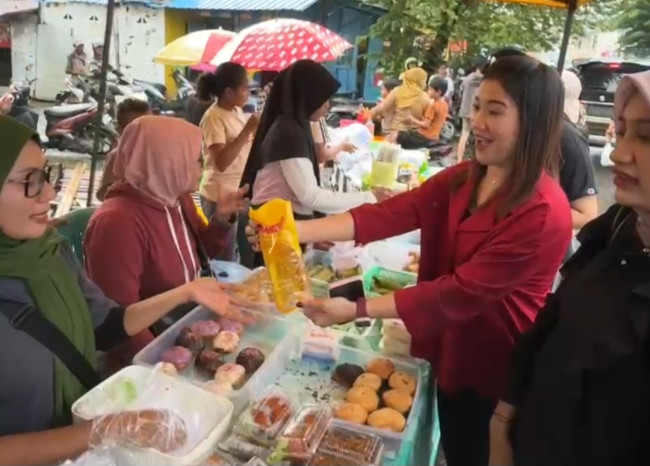 Seorang staf BRI Maumere memberikan minyak goreng kepada saat kepada pedagang takjil di Kampung Beru yang tertarik pada Qris, Kamis (19/2)