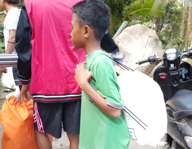 Seorang anak kecil ikut mengambil bantuan di Posko Logistik